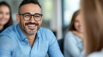 A man wearing glasses is smiling at the camera