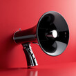 © Alva - A sleek, black megaphone with a shiny, reflective surface set against a bold red background, emphasizing its modern and powerful design.