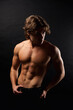 © Alex Vog - Portrait of handsome muscular guy with abs muscle press posing at black backdrop in shadow. Studio shot of sporty healthy strong man with perfect sexy bare torso, advertising model. Copy ad text space