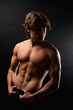 © Alex Vog - Studio shot of sporty healthy strong man with abs muscle press posing at black backdrop in shadow. Portrait of handsome muscular guy with perfect sexy bare torso, advertising model. Copy ad text space