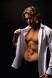 © Alex Vog - Handsome man advertising model in unbuttoned white shirt with abs muscle press posing in shadow at black studio shot. Portrait of stylish guy with perfect muscular sexy torso, pose. Copy ad text space