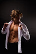 © Alex Vog - Perfect young man advertising model wear unbuttoned white shirt with abs muscle press poses in shadow at black studio shot. Portrait of stylish guy with perfect muscular sexy torso. Copy ad text space