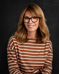 Wall Mural - Studio portrait of a blond haired woman against dark background