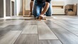 © WITTAYA  ANGMUJCHA - A worker is installing wood-look porcelain tiles in the open-concept living area of a contemporary home