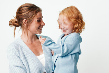 Happy mother holding smiling daughter in arms outdoors, family love and joy concept