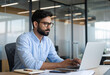© Arshadul - Serious Indian businessman inside his office, a mature man in a shirt and glasses, working diligently on his laptop while pondering a solution to a programming challenge.