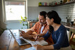 © Geber86 - Couple reviewing documents together while using laptop at home