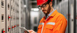 © javu - A safety-conscious technician in an orange uniform and hard hat inspects electrical
