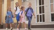 © maxximmm - back to school. a group of schoolchildren with backpacks walk next to the school. education kids concept. schoolboy and schoolgirl going to school. a lifestyle group of children walking