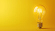 © Andres Mejia - Light bulb shining brightly on a yellow background