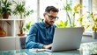 © Kh - A young man working on a laptop computer in an indoor office setting