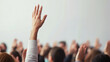© Taskmanager - A close-up of a raised hand in a crowd, symbolizing participation, engagement, volunteering, or asking questions in a group setting such as a classroom, meeting, or seminar.