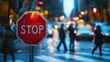 © sirisakboakaew - A stop sign at a busy crosswalk during rush hour, with people walking by and cars patiently waiting