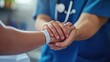 © Dragon - A doctor's hand gently holding a patient's hand with a medical wristband.