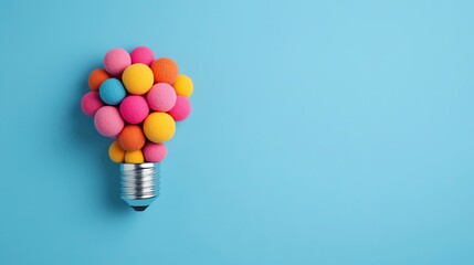 Wall Mural - colorful pom-poms creatively shaped like a light bulb against a blue background, symbolizing creativ