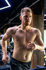 Athlete on a treadmill in the gym. Shirtless man in the gym. Sports lifestyle.