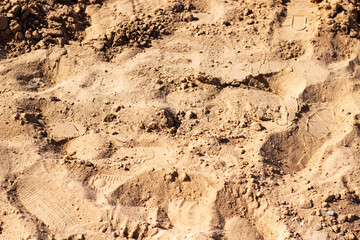 A detailed closeup view showing a pile of dirt that has footprints in it