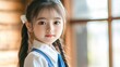 © EarthWalker - Little cute Asian schoolgirl wearing uniform looking into camera indoors. Back to school concept