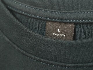 Close up of black t-shirt's round neck collar. Size L oversize t-shirt label tag. Mock up for clothing design