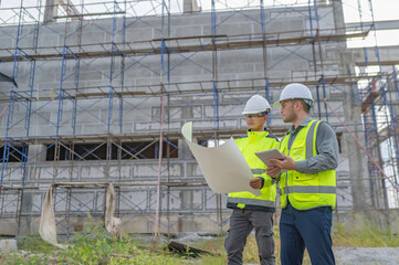 Two Asian engineer working at site of a large building project,Work overtime at construction site,Team of engineer discus at site,The architect, supervisor, and foreman meet to discuss the design