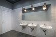 © alhim - Office public bathroom, decorated with white tiles. A large mirror and three sinks.