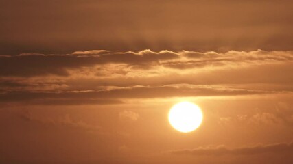 Wall Mural - Fast and falling sun sets behind layers of clouds on a warm summer sky, time lapse.
