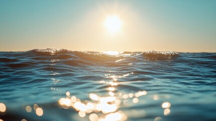 A close-up of the sun sparkling on the surface of the sea, with light dancing on the small waves under a bright blue sky