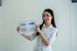 © Wasana - Asian businesswoman holding and pointing at charts on white background