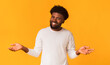© Prostock-studio - Young joyful friendly black man smiling over orange background with arms open, free space