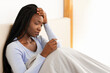 © Prostock-studio - Fever Concept. Sick Afro Woman Holding Thermometer Having Headache And Flu Symptoms Sitting In Bed Indoor. Selective Focus