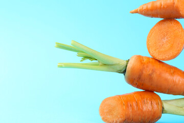 Whole and cut fresh carrots on light blue background, closeup. Space for text