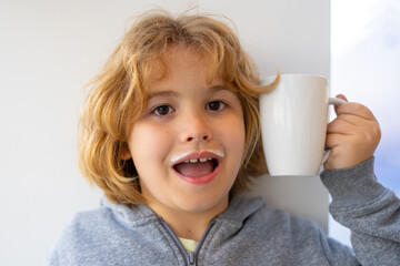 Kid holding a glass of fresh milk. Funny Child with milk moustache drinking milk. Healthy breakfast for children. Healthy eating concept for kids. Little kid boy hold cup of milk.