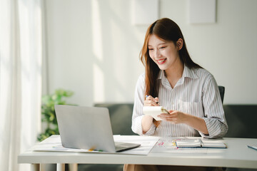 female employee smiling brightly Holding a cup of morning coffee at the office Young woman working on tablet at office Review business documents, audit accounts, search documents, legal documents, cre