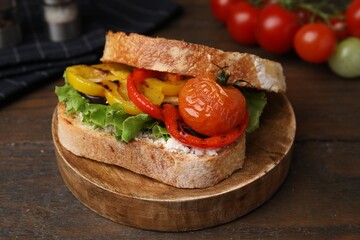 Tasty sandwich with grilled vegetables and cream cheese on wooden table, closeup