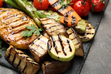 Delicious grilled vegetables and chicken breast on grey table, closeup