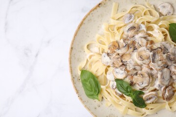 Delicious pasta with mushrooms and basil on white marble table, top view. Space for text