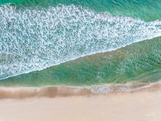 aerial drone view of waves crashing on beach