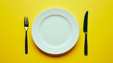 A white plate with a fork and a knife on either side on a yellow background.