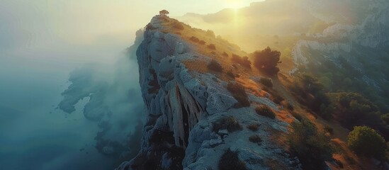 Wall Mural - Majestic mountain peak piercing through misty clouds at dramatic sunset with rugged rocky cliffs and slopes plunging into the valley below  An awe inspiring