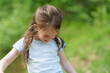 © PeterPike - Little cute preschool girl in a T-shirt plays on the background of a pond. Happy childhood concept outdoors