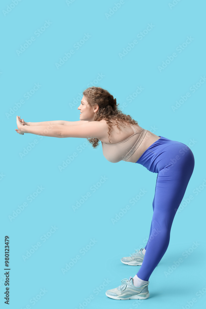 Sporty young woman stretching on  blue background