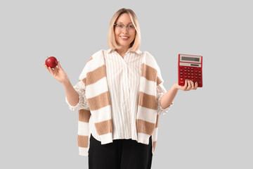 Poster - Mature female math teacher with calculator and apple on grey background