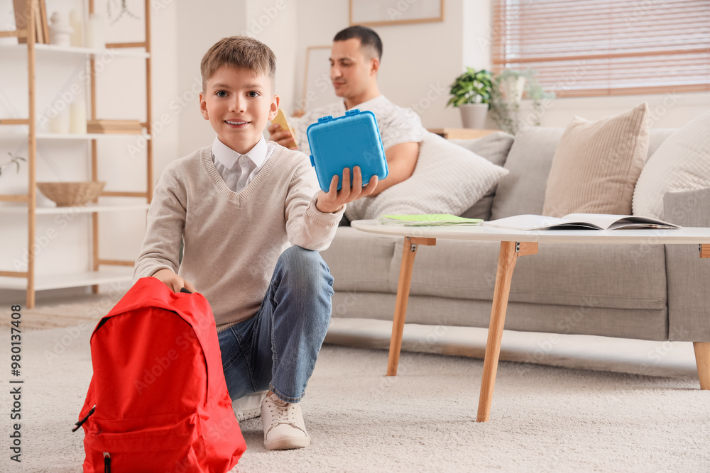 Little boy with school lunchbox and backpack at home