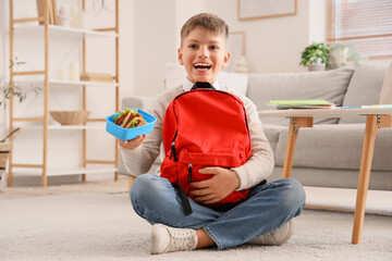 Poster - Little boy with school lunchbox and backpack sitting on floor at home