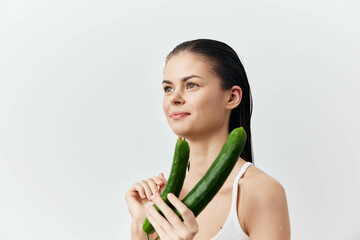 Canvas Print - Woman holding cucumbers with a neutral background, healthy lifestyle concept, freshness, natural beauty, wellness, diet, and healthy eating focus