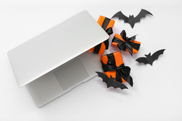 Poster - Laptop with Halloween gift boxes and paper bats on white background