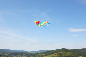 Wall Mural - One colorful kite flying in mountains under blue sky