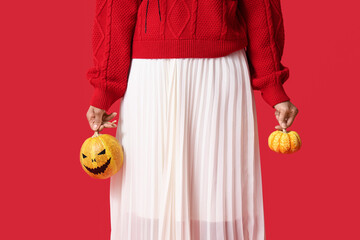 Sticker - Beautiful young happy African-American woman with Halloween pumpkins on red background, closeup