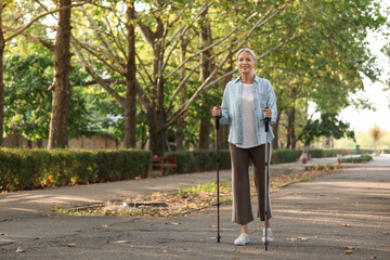 Poster - Beautiful mature happy woman training with walking poles in park