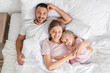 © Pixel-Shot - Happy parents with their little daughter lying under blanket in bedroom, top view